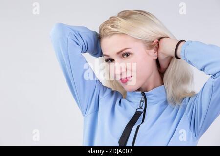 Ragazza tinta bionda venticinque anni su sfondo grigio. Foto Stock