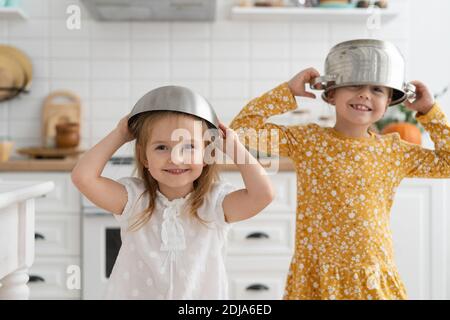 Carino bambini che indossano la ciotola come casco e giocando a casa. Foto Stock