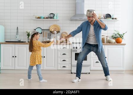 Il padre e la figlia caucasici godono di battaglia divertente attività in cucina trascorri del tempo attivo insieme nel weekend a casa Foto Stock