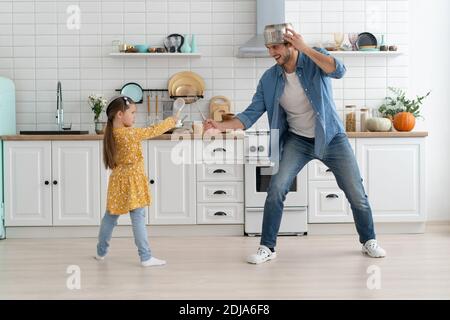 Il padre e la figlia caucasici godono di battaglia divertente attività in cucina trascorri del tempo attivo insieme nel weekend a casa Foto Stock