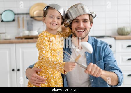 Il padre e la figlia caucasici godono di battaglia divertente attività in cucina trascorri del tempo attivo insieme nel weekend a casa Foto Stock