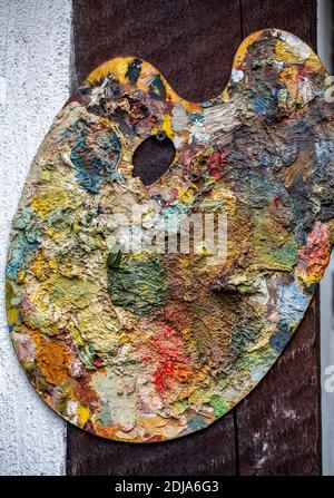 tavolozza del pittore ricoperta da colori di vernice vivaci e misti. Uno sfondo astratto dipinto Foto Stock