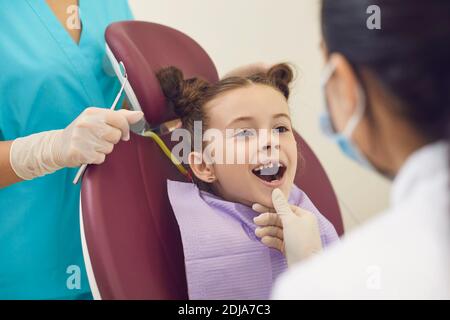 Donna dentista esame sorridente ragazze denti in bocca aperta in clinica dentale Foto Stock