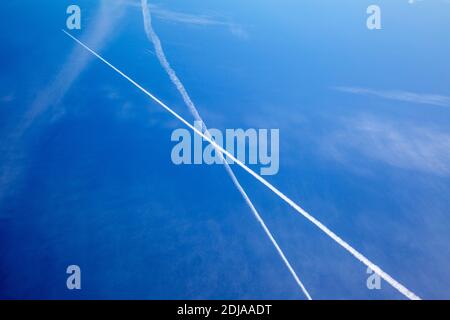 Due aerei contrails che si incrociano l'un l'altro in cielo profondo sfocato Foto Stock