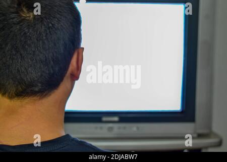 Un uomo da solo sta guardando la televisione. Foto mostra dietro l'uomo e la sua testa e anche in vecchio stile e TV a tubo c'è uno schermo sgranato. Foto Stock