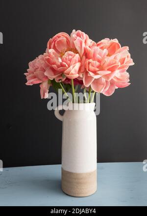 Bouquet di peonie profumate di corallo in una pentola di ceramica bianca. Foto Stock