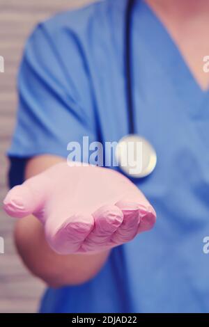 Mano del medico estesa al paziente per una tangente, primo piano. Palmo in un guanto medico che chiede denaro, il concetto di corruzione Foto Stock