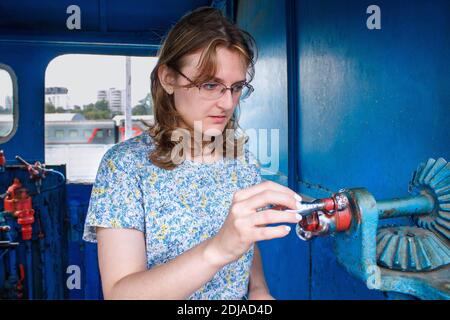 La mano di una donna ruota il dettaglio della locomotiva a vapore. Ritratto femminile sullo sfondo di vecchi meccanismi, stile di vita. Foto Stock