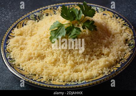 Couscous cotto con prezzemolo verde in piastra di ceramica Foto Stock