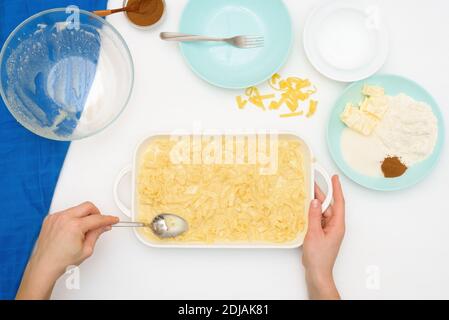 Ricetta dettagliata per la vacanza di Hanukkah, una tradizionale torta Kugel con tagliatelle e crema pasticcera, briciole di sabbia in cima. Ingredienti nei piatti su a. Foto Stock