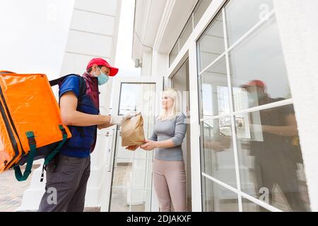 uomo di consegna con zaino termico e donna d'affari in ufficio Foto Stock