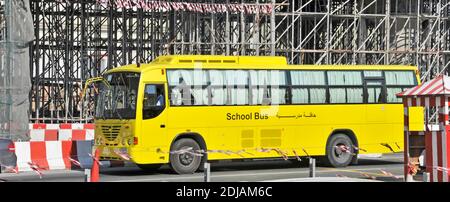 Autobus giallo della scuola di Dubai che passa attraverso impalcature intorno alla costruzione di un ponte Cantiere nuovo sistema di trasporto aereo della metropolitana Emirati Arabi Uniti Foto Stock