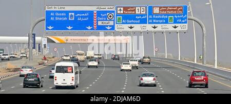 Traffico automobilistico di Dubai sulla moderna autostrada a sette corsie bilingue Indicazioni per l'uscita del gantry per i terminal 1 e 4 dell'aeroporto Uniti Emirati Arabi Uniti Medio Oriente Foto Stock