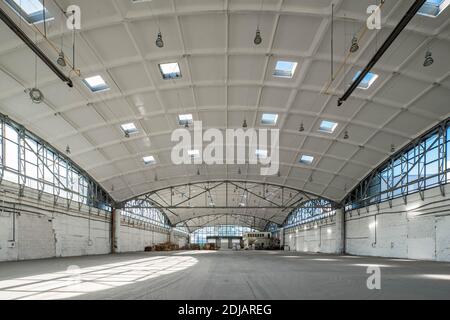 Impilare pallet in legno in un enorme magazzino industriale vuoto. Interno bianco. Tetto portante in cemento armato emisferico con finestre. Arco moderno Foto Stock