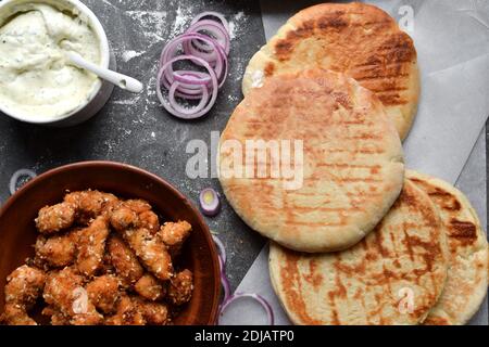 Ingredienti per preparare la pita con il pollo. Fast food sano. Sfondo scuro. Pomodori, cipolla rossa, nocciole di pollo. Foto Stock