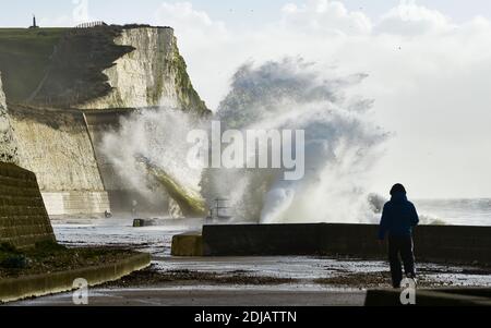 Brighton UK 14 dicembre 2020 - i camminatori guardano le onde che si infrangono a Saltdean Undercliff Walk sul lungomare vicino a Brighton durante i forti venti ad alta marea . Le previsioni del tempo sono per i venti e le docce più forti da spargere attraverso le parti della Gran Bretagna ma con le temperature che sono più calde che nei giorni recenti: Credit Simon Dack / Alamy Live News Foto Stock