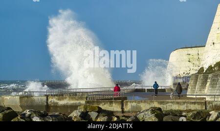 Brighton UK 14 dicembre 2020 - i camminatori guardano le onde che si infrangono lungo la passeggiata sotto la scogliera di Saltdean in una giornata ventosa vicino a Brighton oggi in alta marea . Le previsioni del tempo sono per i venti e le docce più forti da spargere attraverso le parti della Gran Bretagna ma con le temperature che sono più calde che nei giorni recenti: Credit Simon Dack / Alamy Live News Foto Stock