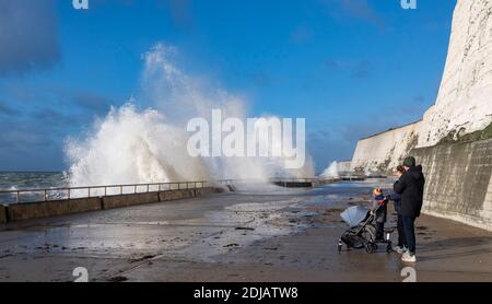 Brighton UK 14 dicembre 2020 - i camminatori guardano le onde che si infrangono in una giornata ventosa lungo la passeggiata sotto la scogliera di Saltdean sul lungomare vicino a Brighton ad alta marea . Le previsioni del tempo sono per i venti e le docce più forti da spargere attraverso le parti della Gran Bretagna ma con le temperature che sono più calde che nei giorni recenti: Credit Simon Dack / Alamy Live News Foto Stock