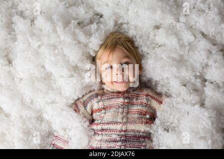 Carino bambino, con il giocattolo lavorato a maglia, giocando nella neve con colorati pupazzi di neve, sorridendo felicemente Foto Stock