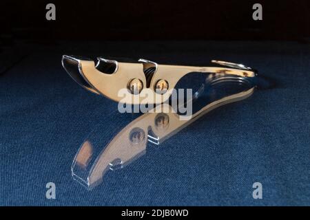 L'affilatura del coltello dagli acciai poggia su turn blu il tavolo con riflessione. Accessori da cucina su sfondo nero Foto Stock