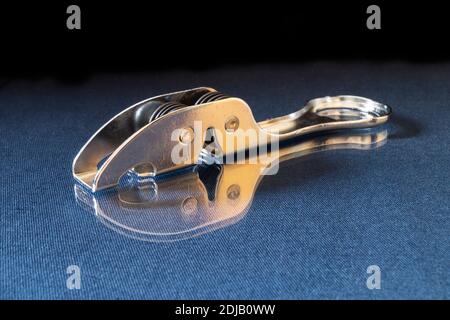 L'affilatura del coltello dagli acciai poggia su turn blu il tavolo con riflessione. Accessori da cucina su sfondo nero Foto Stock