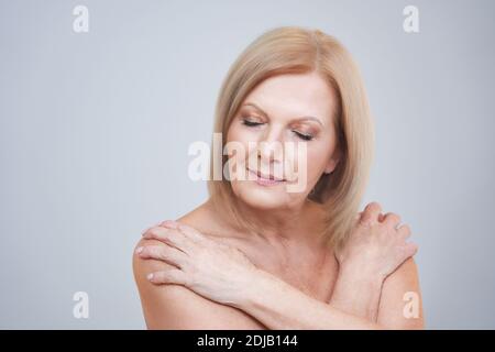 Donna anziana che posa su sfondo grigio Foto Stock