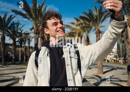 Giovane attraente uomo allegro felice di prendere selfie sullo smartphone dentro parcheggio Foto Stock