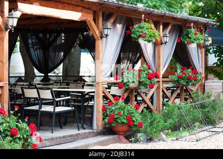 Terrazza estiva in un caffè di strada con fiori rossi in pentole Foto Stock