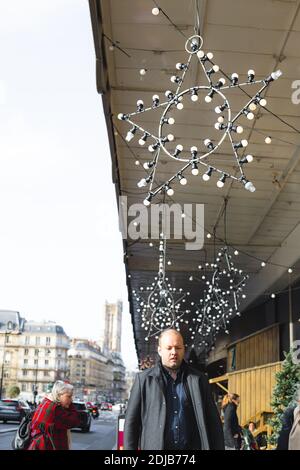 Parigi Francia 21 12 2019 persone passano per le strade di Parigi durante il Capodanno e le vacanze di Natale. Case facciata decorata con stella fatta di lampade Foto Stock