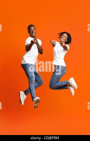 Felici amanti del nero che posano su sfondo arancione studio Foto Stock