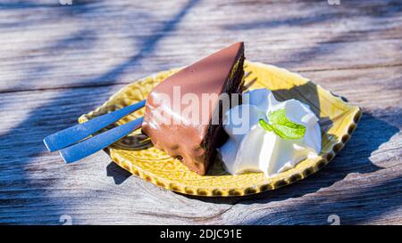 torta di cioccolato fondente servire con crema su tavolo di legno vintage. Foto Stock