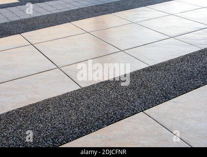 La diversa consistenza della superficie dei diversi materiali di pavimentazione su il marciapiede dell'edificio Foto Stock