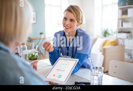Operatore sanitario o operatore sanitario con paziente anziano, misurando la glicemia all'interno. Foto Stock