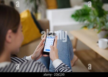 Giovane donna con smartphone che ordina cibo a casa, coronavirus e concetto di consegna di cibo. Foto Stock