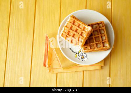 Due deliziosi waffle su sfondo giallo e arancione piatto Foto Stock