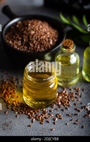 Bottiglia di olio di semi di lino e semi di lino nel recipiente. Foto Stock