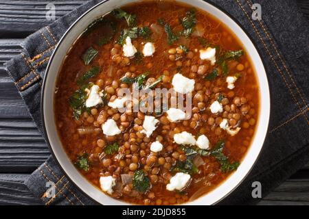 Deliziosa zuppa con lenticchie marroni e feta in primo piano in un piatto sul tavolo. Vista dall'alto orizzontale Foto Stock