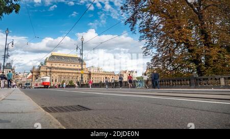 Il Ponte di Legions, Praga, Repubblica Ceca. Scena di strada con un tram tradizionale che passa davanti all'elaborato Teatro Nazionale. Foto Stock