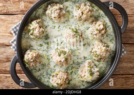 Yuvarlakia è un piatto greco di polpette condite con un Avgolemono o salsa di limone d'uovo primo piano in un piatto sul tavolo. Vista dall'alto orizzontale da Foto Stock