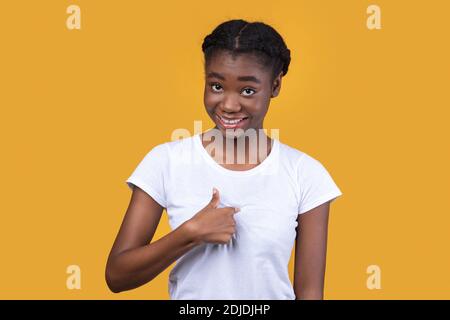 Sorridente giovane donna africana che punta il dito verso se stessa, Studio Shot Foto Stock