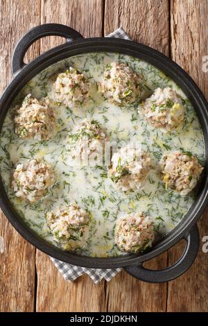 Polpette greche con riso in salsa di yogurt con primo piano di limone in un piatto sul tavolo. Vista dall'alto verticale Foto Stock