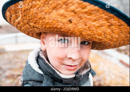 Un piccolo ragazzo sporco come un contadino nel cappello di paglia Foto  stock - Alamy