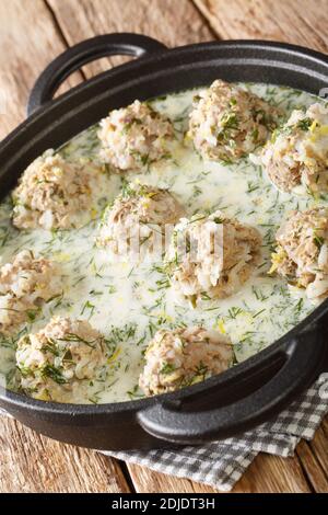 Polpette greche con riso in salsa di yogurt con primo piano di limone in un piatto sul tavolo. Verticale Foto Stock