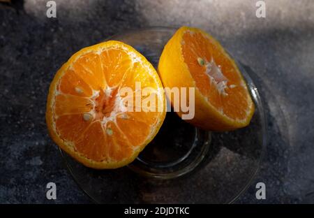 due pezzi di arancio a metà taglio, in un piatto su sfondo scuro Foto Stock