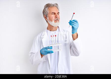 lo scienziato di laboratorio conduce l'esperienza o le analisi. 2019-nCoV, coronavirus. Natura vecchio maschio esperto in tuta medica esaminare la provetta Foto Stock