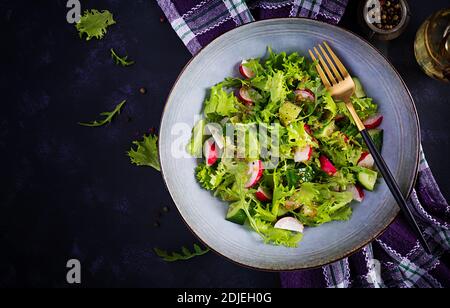 Insalata fresca e sana di cetrioli, ravanelli ed erbe con condimento al miele di senape. Vista dall'alto, dall'alto Foto Stock