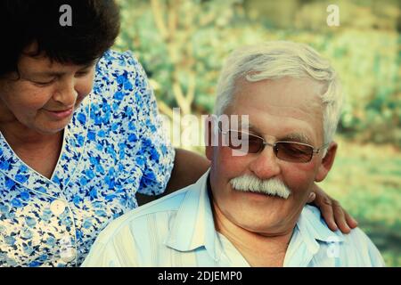 Abbracci di persone mature amorevoli in una giornata estiva nel park.Senior coppia sono seduti outdoors.An anziana donna abbracci un vecchio uomo Foto Stock