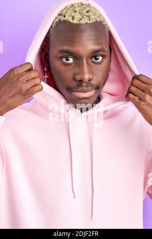 l'uomo calmo afro indossa il cappuccio del pullover, guarda la fotocamera con uno sguardo profondo. riprese da studio isolate Foto Stock