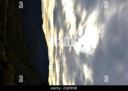 Cielo rotto al tramonto con turbine eoliche in montagna. Foto Stock