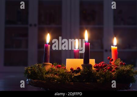 Corona dell'Avvento di Natale con candele che bruciano luminose in camera buia Foto Stock